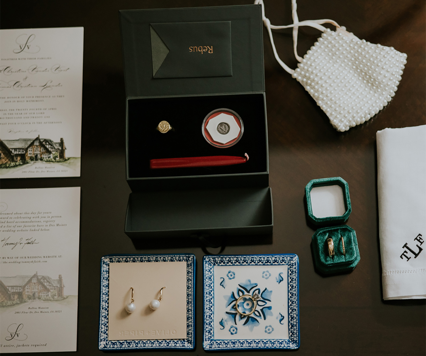 Aerial photograph of wedding paraphernalia including pearl earrings, gold signet ring, embroidered handkerchief, and wedding invitation 